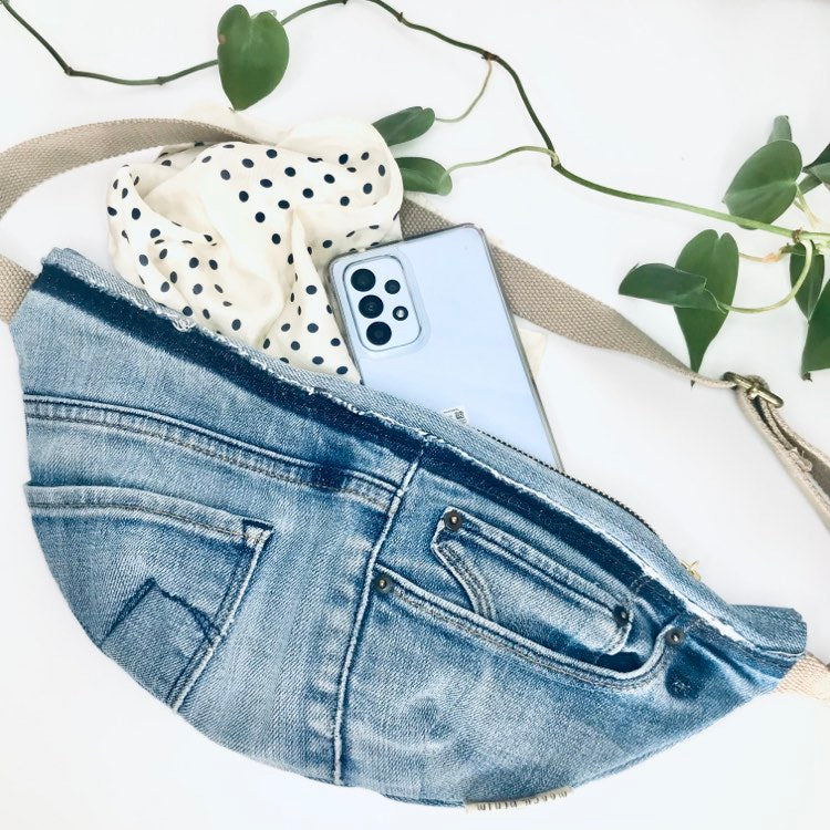 Waist pouch made with upcycled blue denim containing a phone and scarf inside